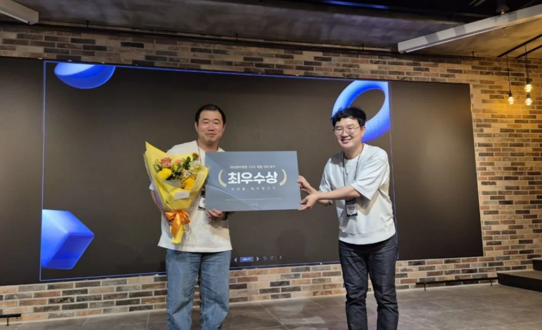 CEO Kim Dae-hee holding a bouquet and the top-award plaque on stage at the TAB Angel Partners demo day